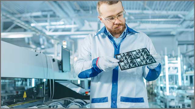 An image of an industrial employee working on a PCB