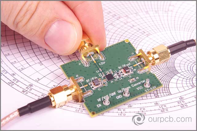 Repeatable detection performance. Radiofrequency engineer inspect microwave mixer printed circuit board in front of Smith chart