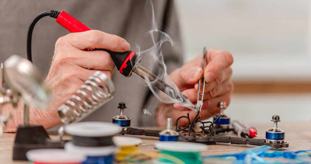 A technician repairing a drone’s circuit using a soldering iron