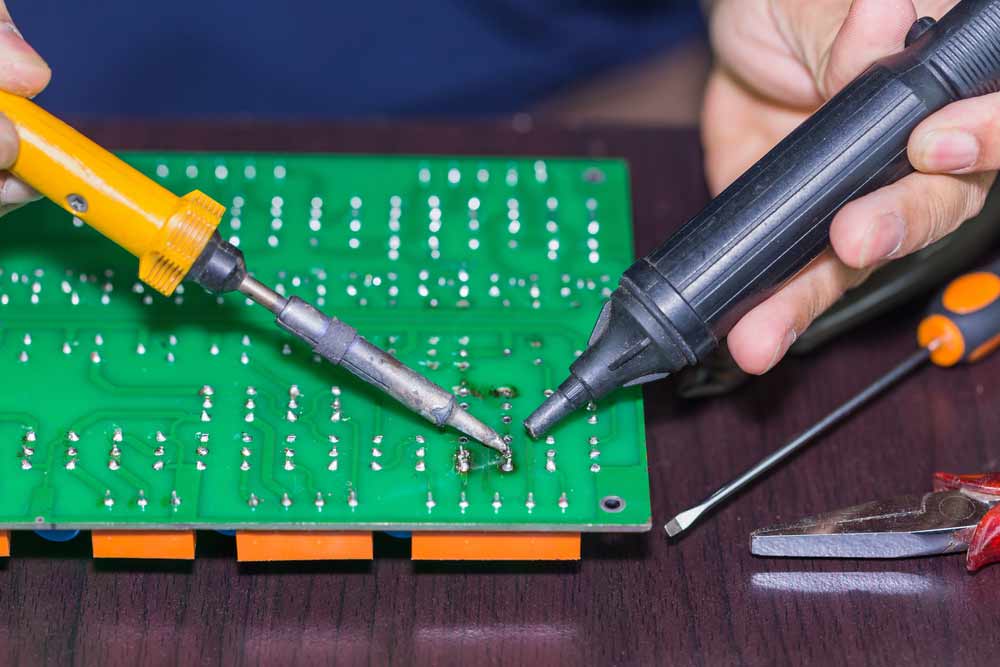 PCB component desoldering using a soldering iron and a vacuum plunger