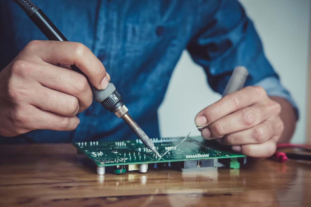A technician hand-soldering a circuit board
