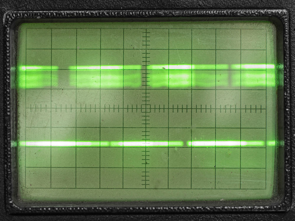 Old green analog oscilloscope display with pulse image.