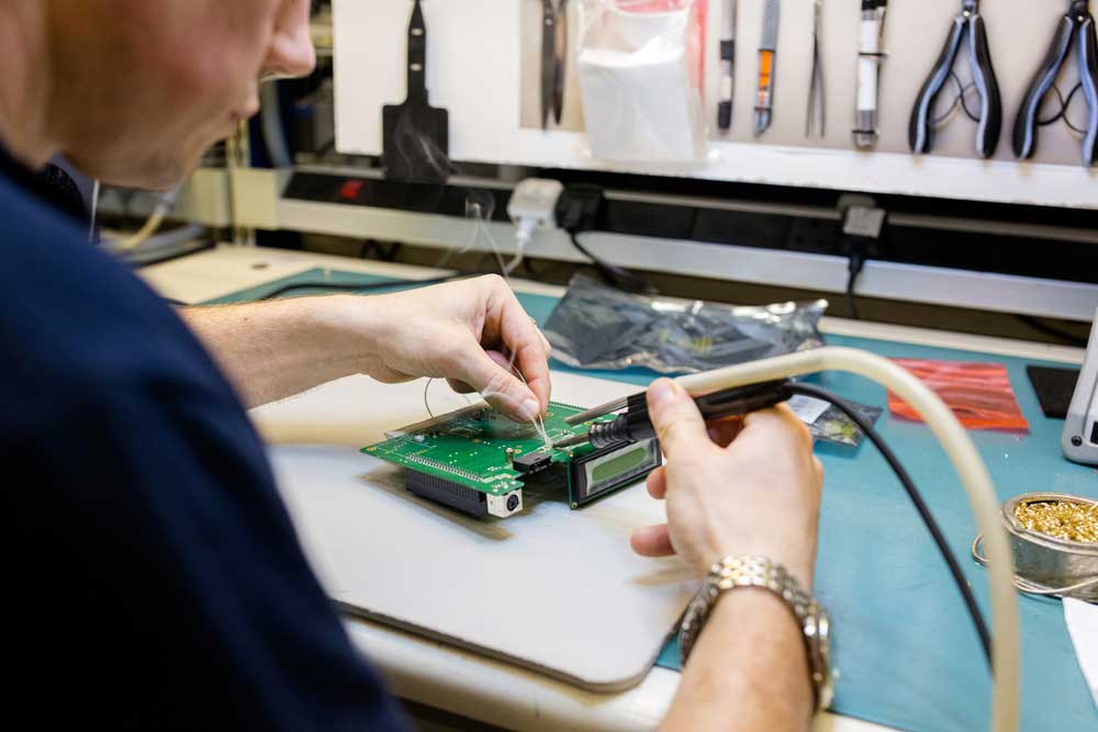 94v0--A man using a soldering iron on a circuit board