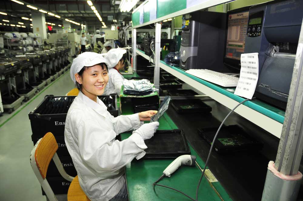 Worker checking an integrated circuit board in a factory