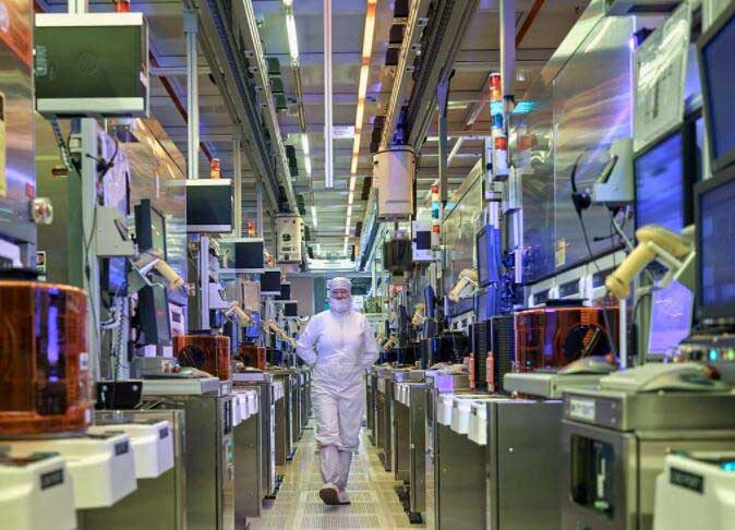The worker walks through the floor of Intel’s wafer production plant.