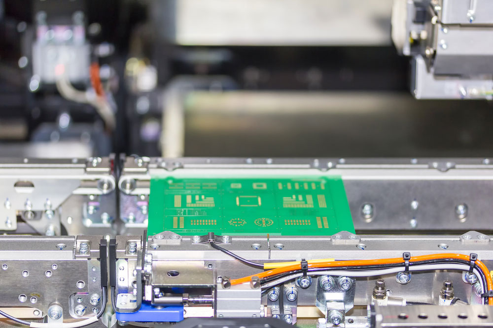 A circuit board on the conveyor of an SMT pick and place machine 