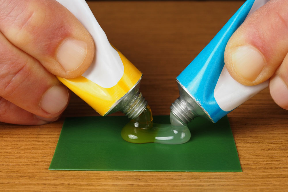 Two hands combining epoxy to create an adhesive
