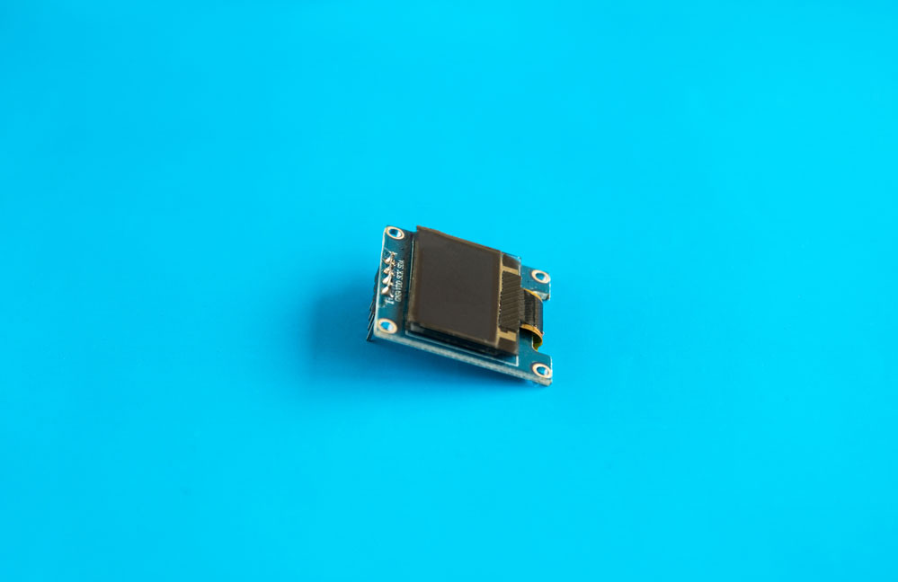 SSD1306 OLED display module tilted in front of blue background