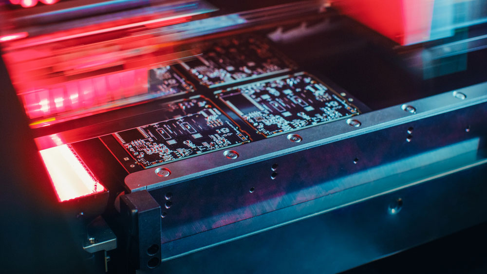 Printed Circuit Board Being Assembled with Automated Robotic Arm, Surface Mounted Technology Connecting Microchips to the Motherboard.