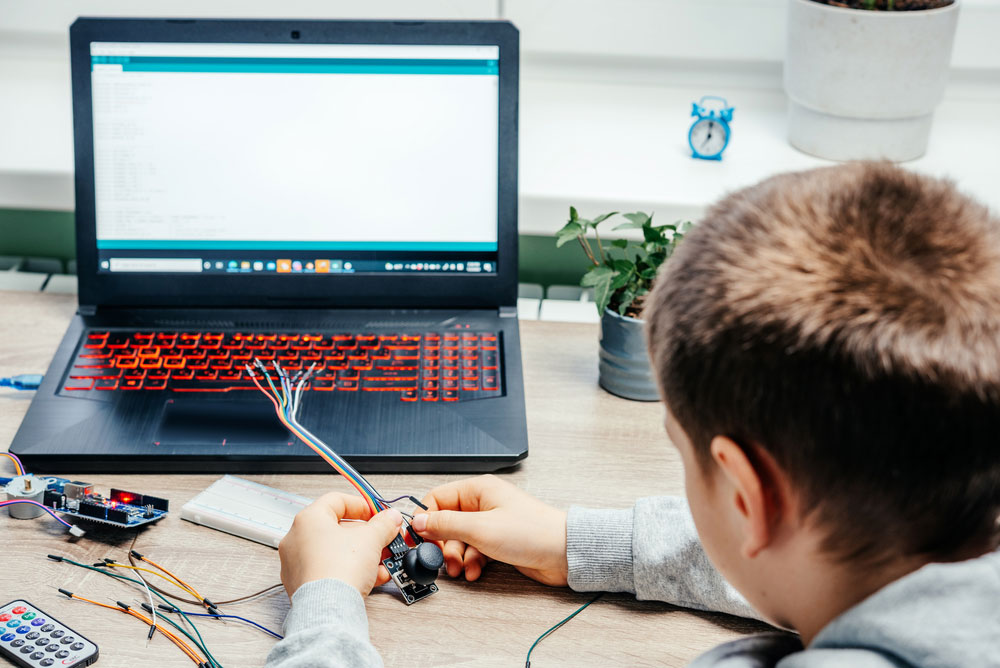 Boy creating a project with Arduino and laptop.