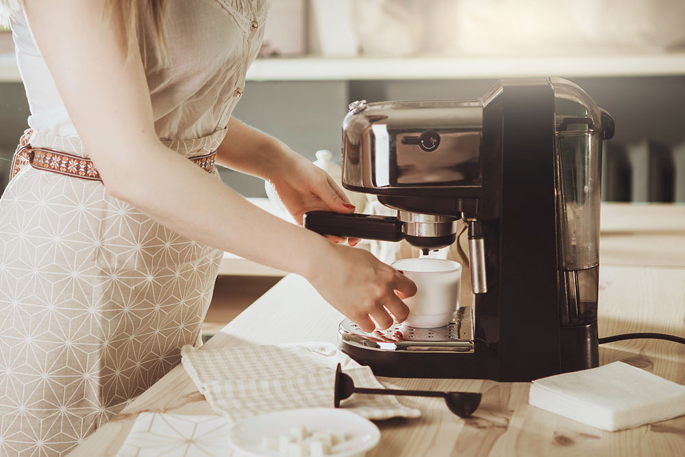 Woman making fresh espresso in the coffee maker.