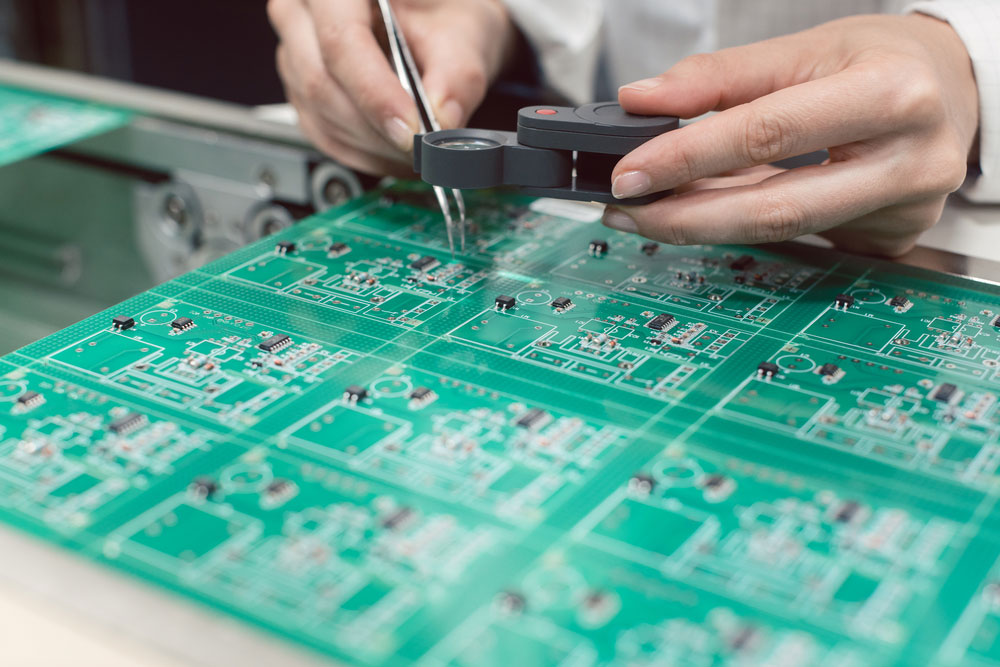 Technician inserting electronic components into a PDB for assembly