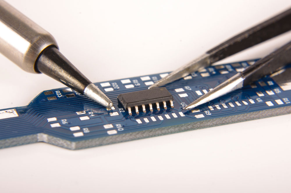Small electronics integrated circuit IC on empty PCB board ready for hand assembly