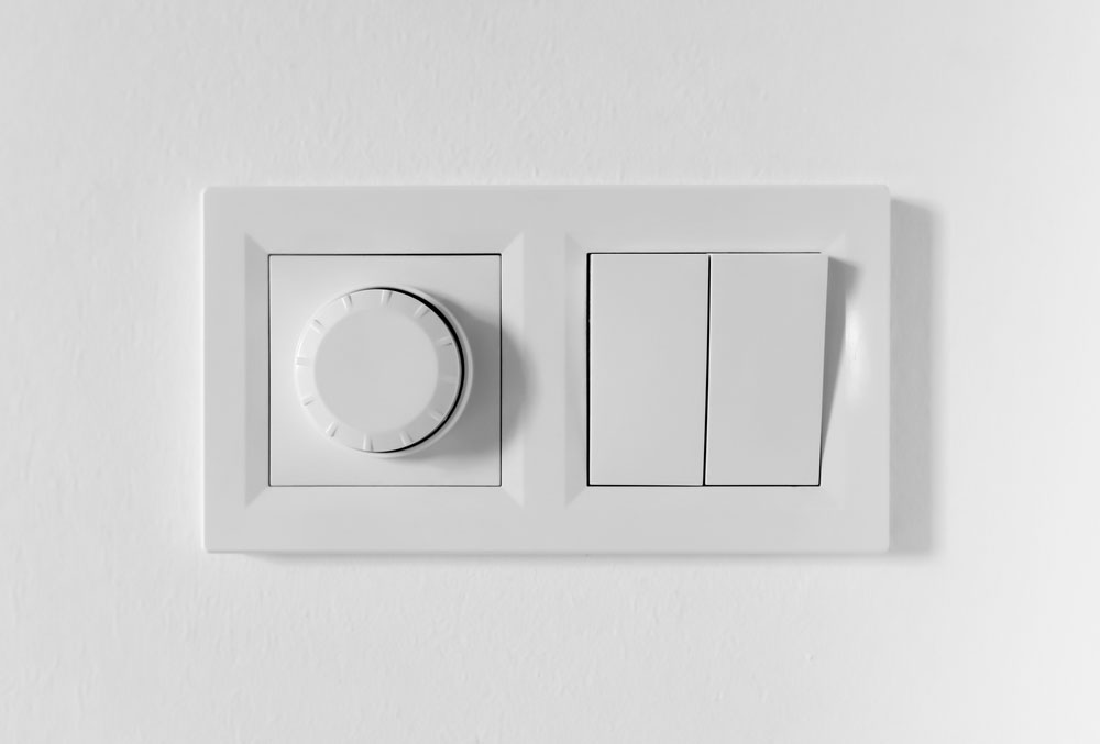 A dimmer switch alongside regular on/off switches