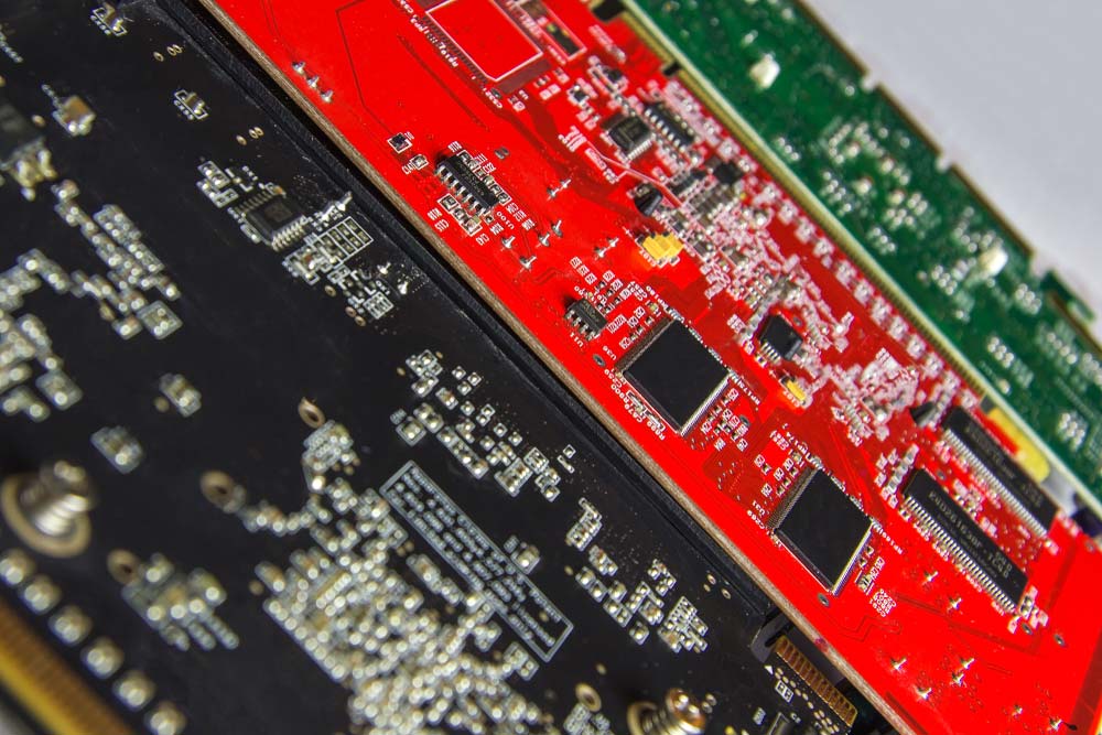 Three printed circuit boards with black, red, and green solder masks