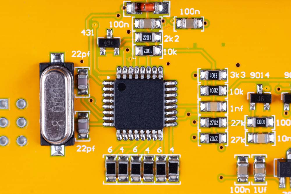 A yellow PCB with a microchip in the middle