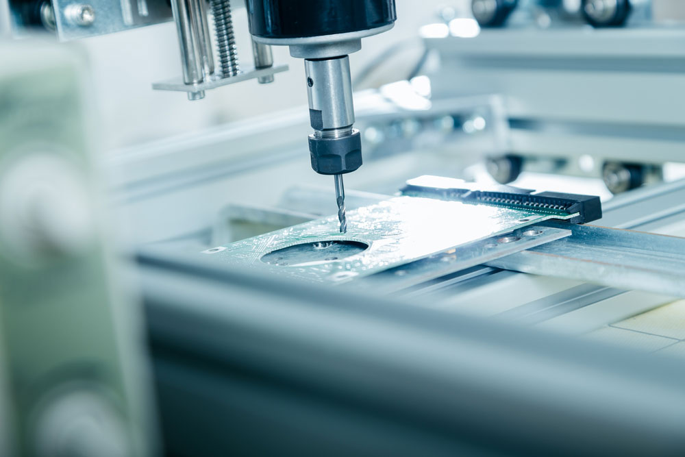 A CNC machine drilling a PCB material