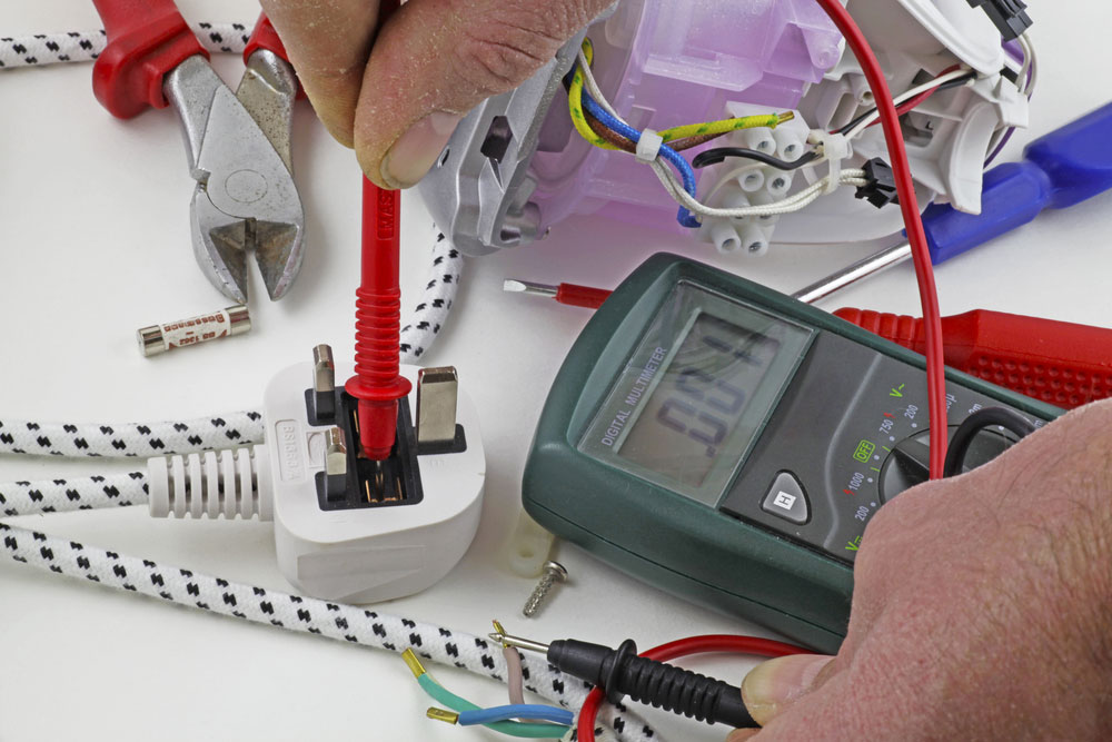 An electrician carrying out a continuity test on a plug’s live cable using a multimeter