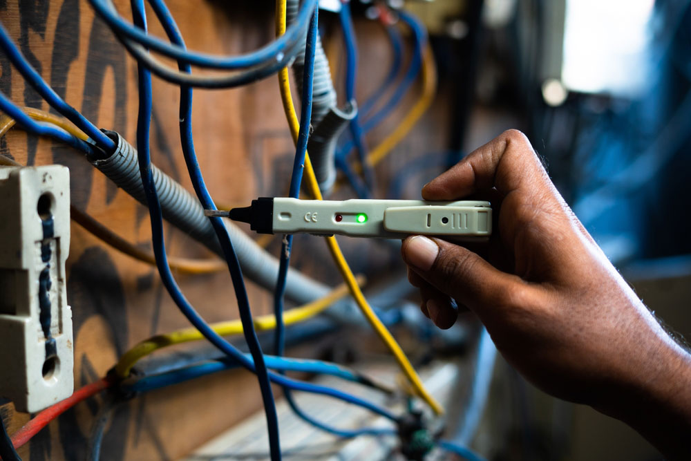 An electrician testing current flow using a continuity tester