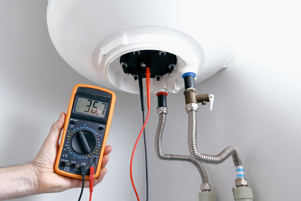 An engineer using a multimeter to test for continuity in a new heating element after installation