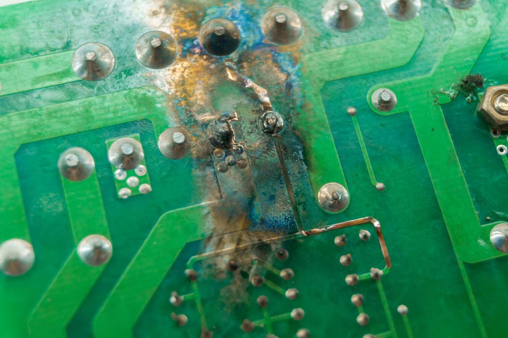 A PCB with a shorted section that has discolored the green solder mask.