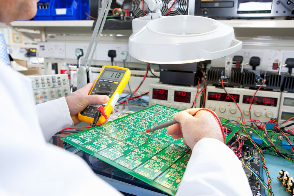 An engineer examining a circuit board using a digital multimeter