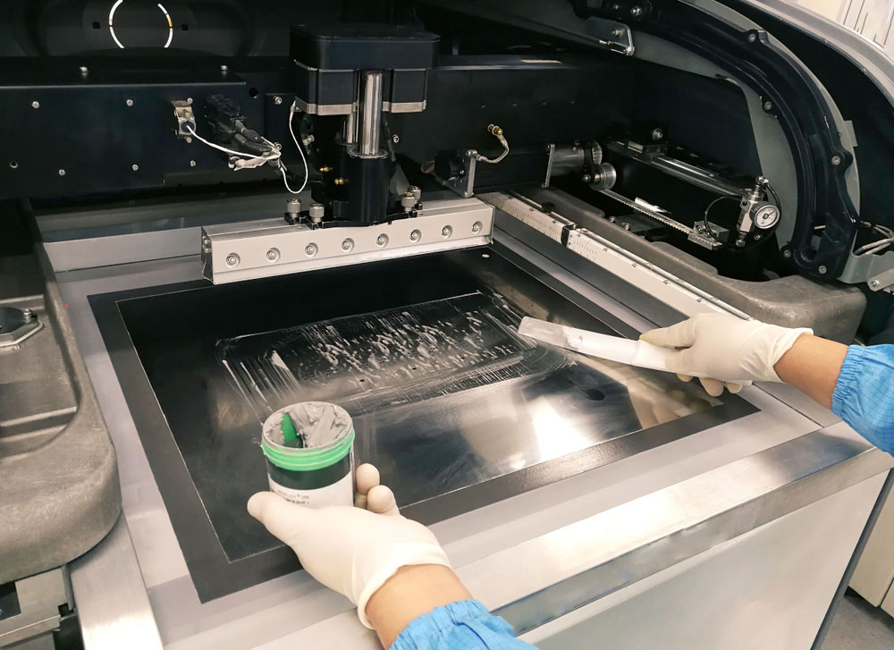 A worker applying solder paste on a stencil for PCB production