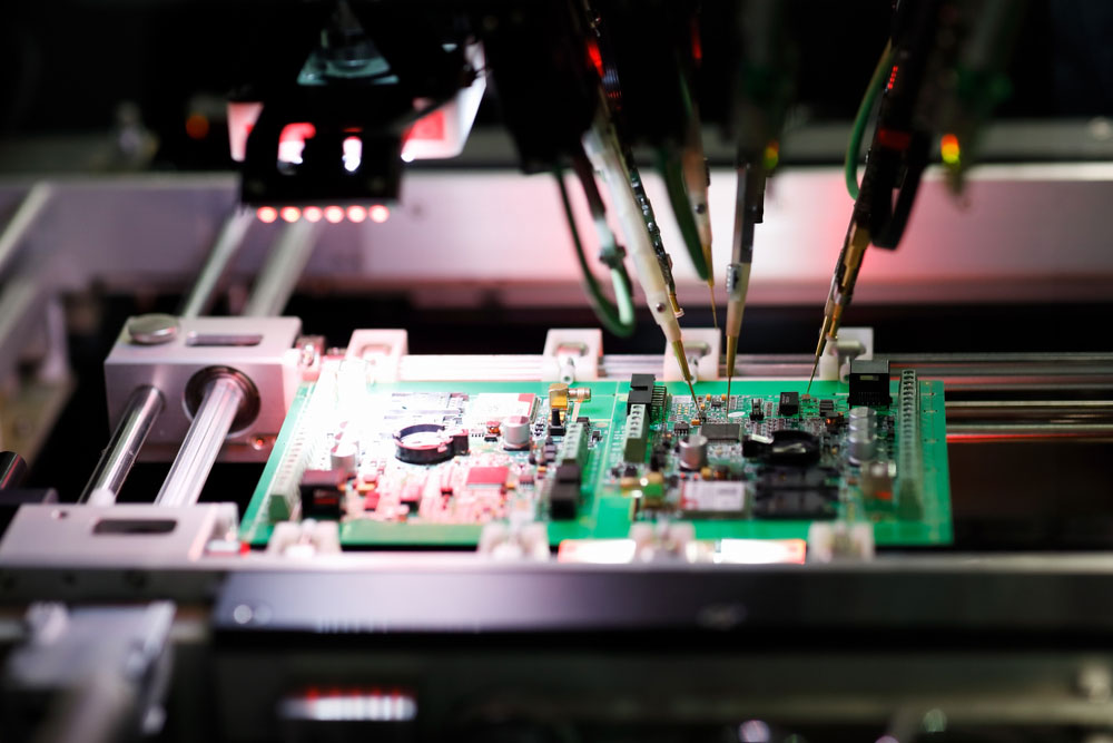 A printed circuit board assembly undergoing a flying probe in-circuit test in a flying probe tester