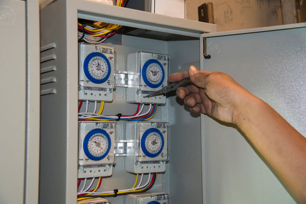 An engineer checking four analog timer switches