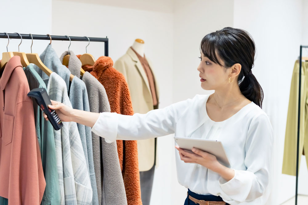 A store clerk using RFID to read data from clothes for stocktaking or inventory management