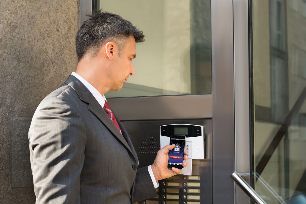 A man using a smartphone to disarm a door’s security system