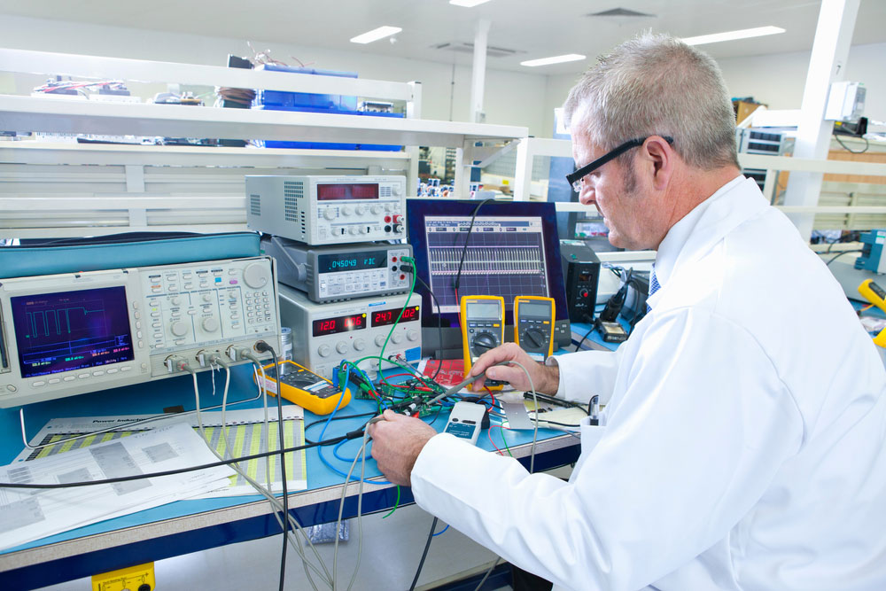 An engineer on a workbench with several instruments, including an oscilloscope