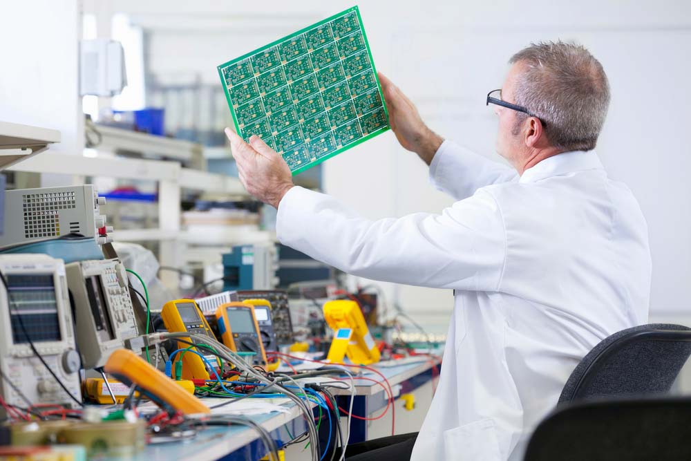 An electrical engineer examining PCBs on a test bench