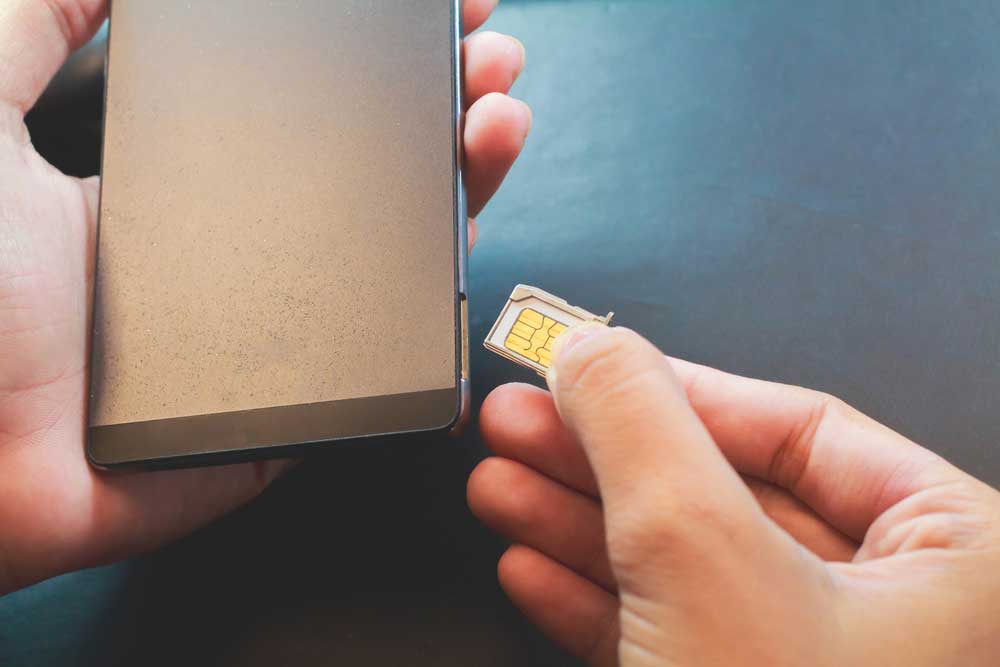 A person inserting a nano SIM card into a smartphone
