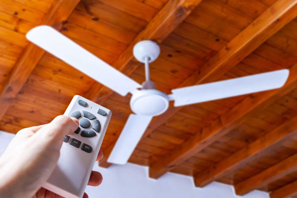 A person controlling a ceiling fan using a remote control