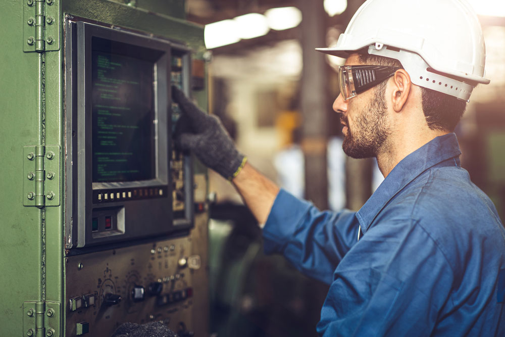 A machinist operates a machine from the G-Code monitor