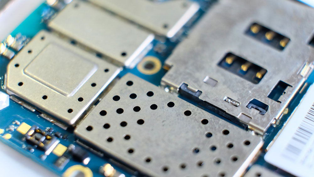 A microchip and electrical components are covered using a shield on a PCB