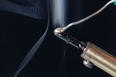 Molten solder at the tip of a soldering iron
