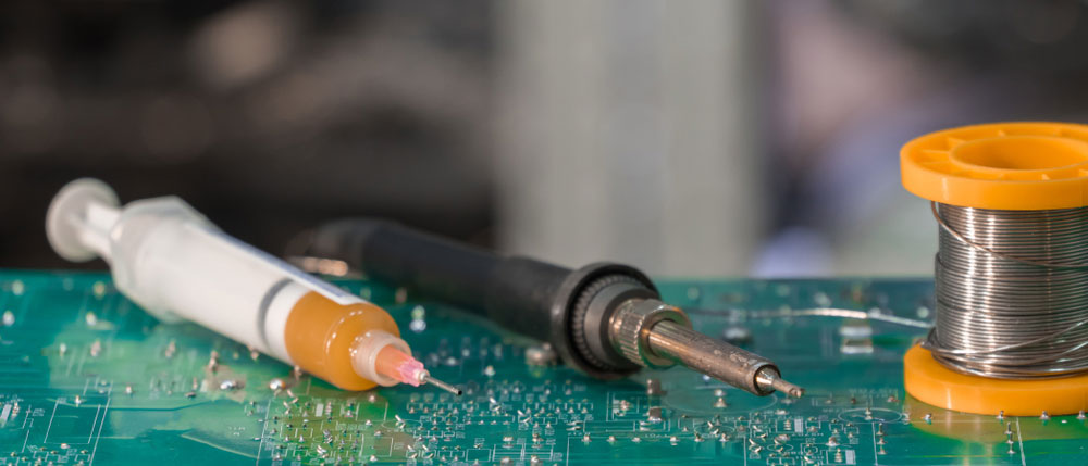 Soldering tools ready for work on a PCB (note the solder flux in the syringe)