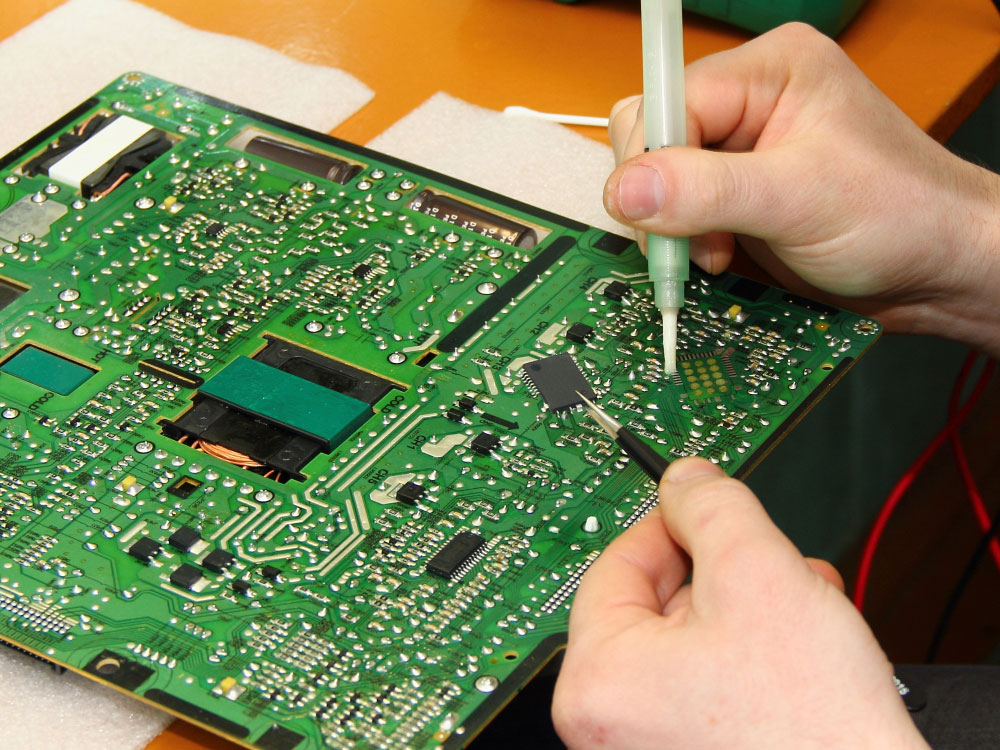 A technician with flux solder and chip held using tweezers ready for soldering