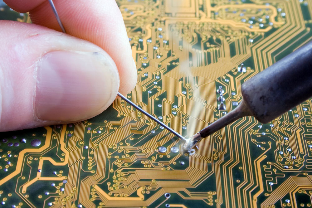 A technician soldering an electronic PCB