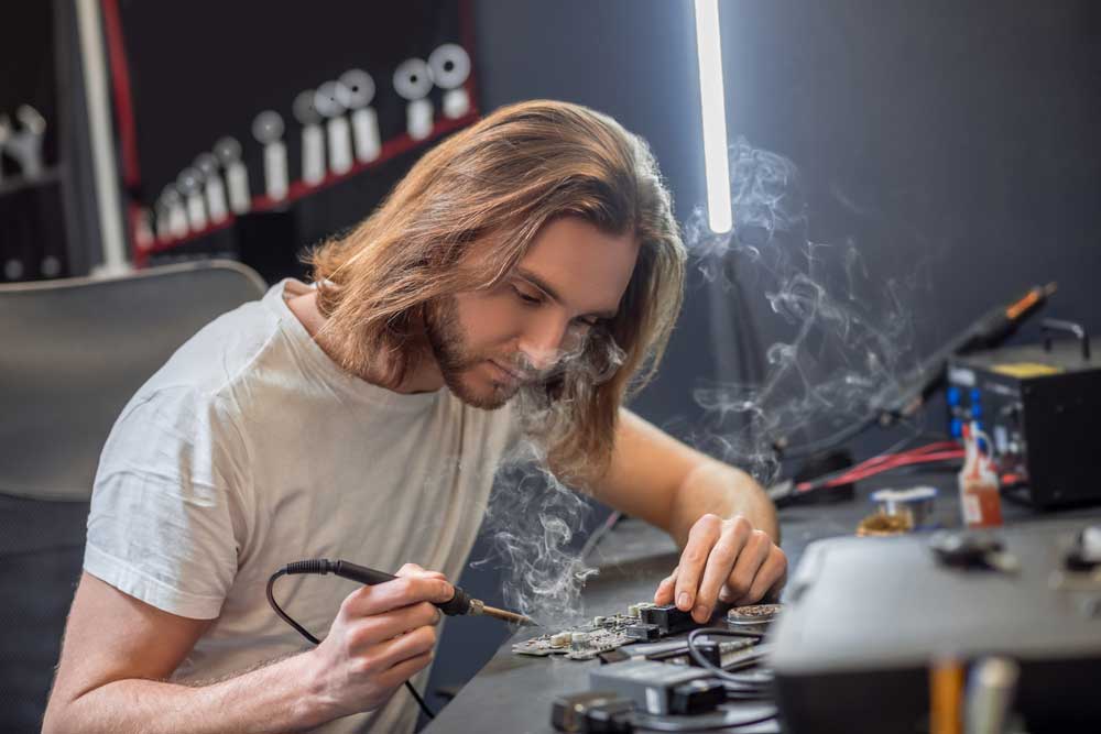 A technician manually soldering PCB components.