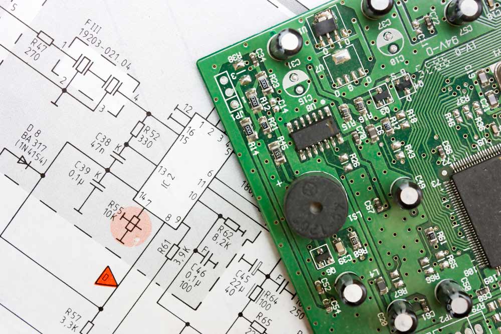 A PCB is placed against its schematic for easy mapping