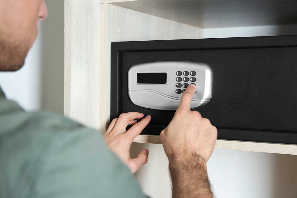 A man entering a code on a steel safe with an electronic lock in a hotel room