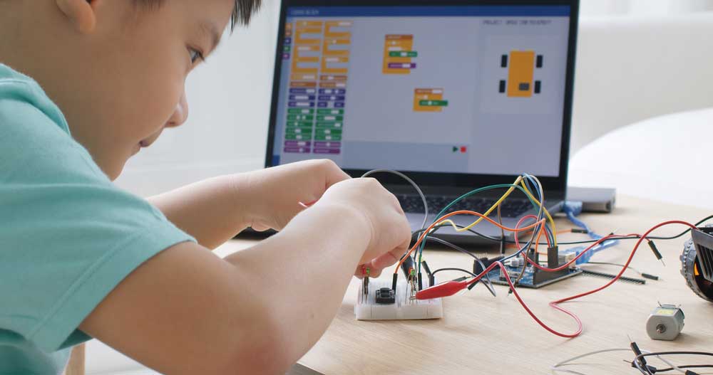 A young lad assembling an Arduino project before programming using block codes