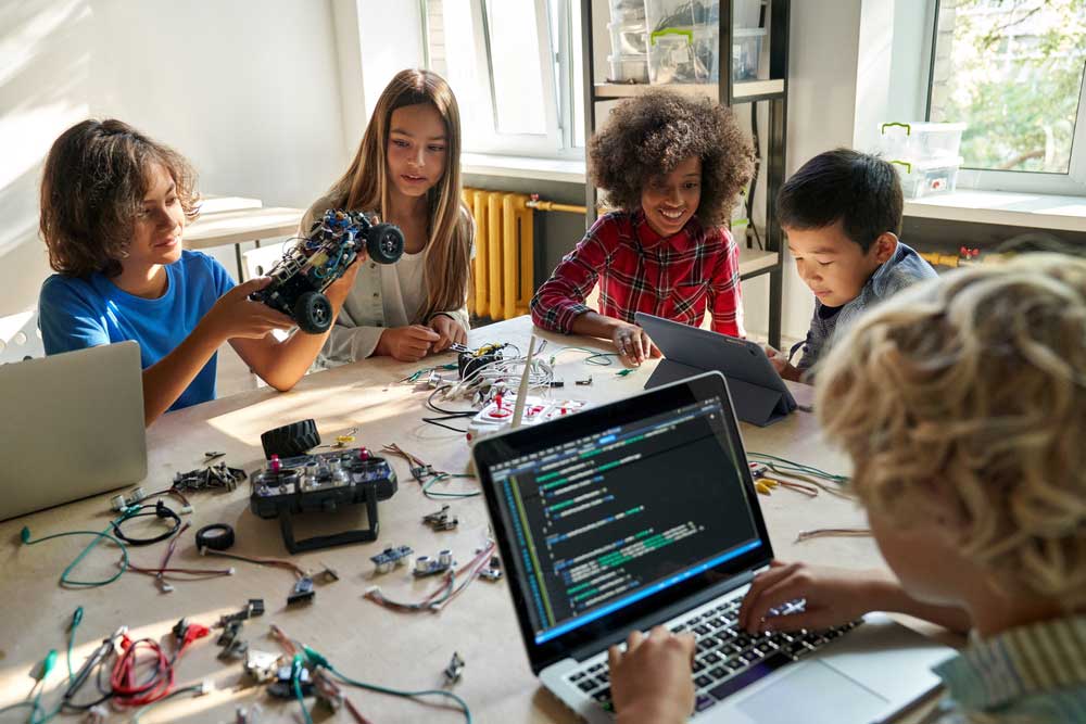 Several kids using Arduino block programming to code robotic cars