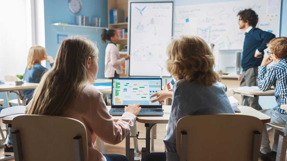 Two elementary school kids discussing a block programming project